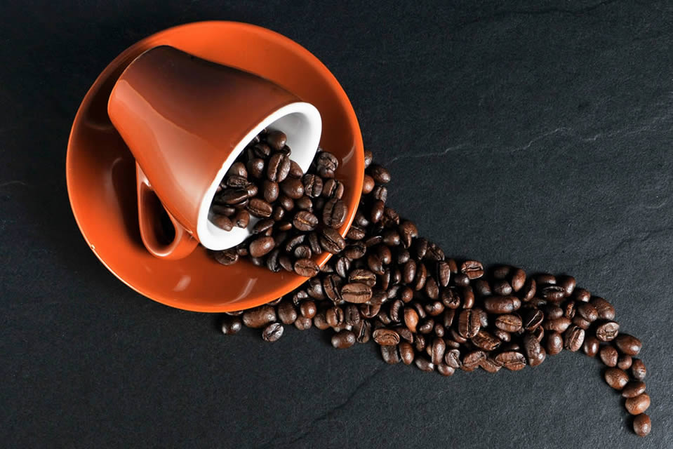 tazzina ribaltata con chicchi di caffe interi